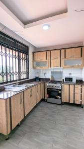 a large kitchen with wooden cabinets and a stove at NL Josephine's Apartment in Kampala