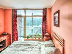a bedroom with orange walls and a large window at Studio Čertovka-3 by Interhome in Harrachov