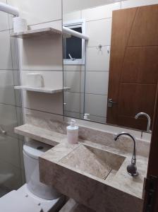 a bathroom with a sink and a toilet and a mirror at Apartamento completo com wi-fi e piscina in Ubatuba +27 photos