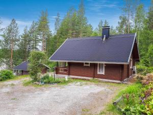 a house with a black roof in the woods at Holiday Home Nurmirinne by Interhome in Nurmes +14 photos