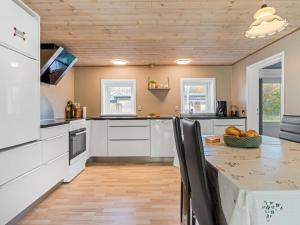 a kitchen with white cabinets and a wooden ceiling at Holiday Home Emelia - 4-2km from the sea by Interhome in Byrum