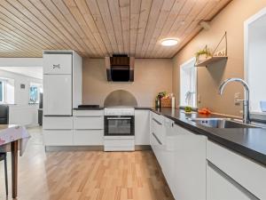 a kitchen with white cabinets and a wooden ceiling at Holiday Home Emelia - 4-2km from the sea by Interhome in Byrum