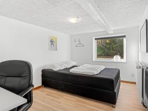 a bedroom with a bed and a chair in a room at Holiday Home Emelia - 4-2km from the sea by Interhome in Byrum +2 photos