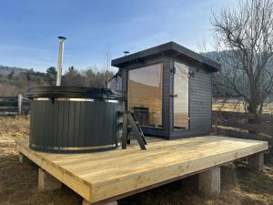 a tiny house on a wooden deck with a jacuzzi at K&N vendégház in VoÅŸlobeni