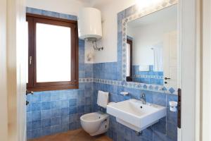 a blue tiled bathroom with a sink and a mirror at Baia dei Mirti 4 people Apartment in Vignola Mare