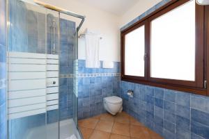 a blue tiled bathroom with a toilet and a shower at Baia dei Mirti 4 people Apartment in Vignola Mare