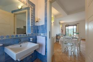 a bathroom with a white sink and a table at Baia dei Mirti 4 people Apartment in Vignola Mare +12 photos