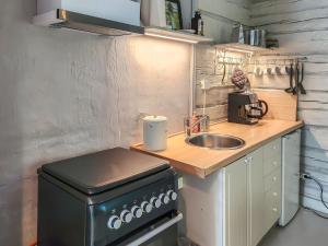 Holiday Home Den lilla röda stugan by Interhome في Kårkulla: مطبخ صغير مع حوض وموقد