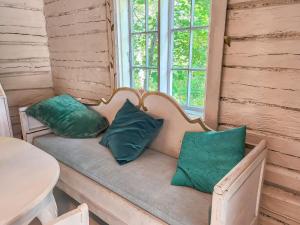 Holiday Home Den lilla röda stugan by Interhome في Kårkulla: مقعد عليه وسادتان خضراوان موضوع في غرفة