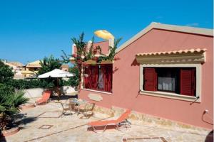 a pink house with chairs and a table and a patio at Krista House in Agios Gordios +10 photos