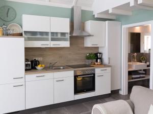 een keuken met witte kasten en een spoelbak bij Ferienhaus Clara in Klein Scharrel +17 foto's