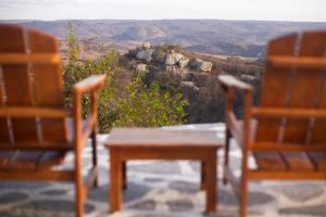 two chairs and a table on a patio with a view at Olymp Spa Boutique Hotel in Monte das Gameleiras