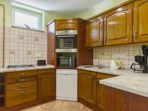 a kitchen with wooden cabinets and a white dishwasher at Apartment Pajtas 2 by Interhome in Balatonfenyves