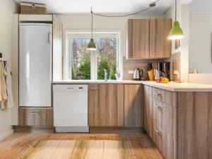 a kitchen with wooden cabinets and a white refrigerator at Holiday Home Paule - 1-3km from the sea by Interhome in Vesterø Havn