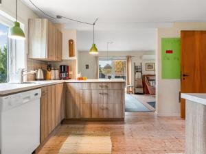 a kitchen with wooden cabinets and white appliances at Holiday Home Paule - 1-3km from the sea by Interhome in Vesterø Havn