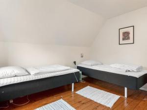 two beds in a room with white walls and wooden floors at Holiday Home Paule - 1-3km from the sea by Interhome in Vesterø Havn +4 photos