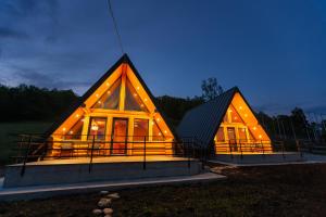 a large wooden house with lights on it at night at Chilia Houses in Mănăstirea Humorului