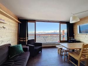 - un salon avec un canapé, une table et une grande fenêtre dans l'établissement Apartment La Nova-2 by Interhome, à Arc 1800