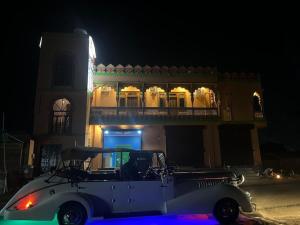 een witte auto geparkeerd voor een gebouw 's nachts bij Hotel Simran Desert View Haveli in Pushkar