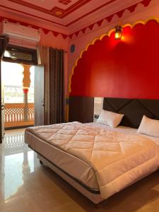 een slaapkamer met een groot bed met een rode muur bij Hotel Simran Desert View Haveli in Pushkar +10 foto's