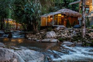 a cabin in the woods next to a stream at เดอะริเวอร์ แม่กำปอง The River Maekampong Chiang Mai in Ban Pok Nai