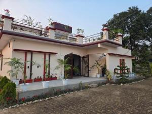 Jim Corbett Guest House في Jhirna: منزل مع شرفة فوقه