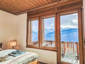 a bedroom with a large window with a view of mountains at Apartment Möösli Vue by Interhome in Sundlauenen