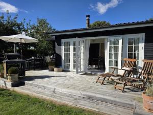 Holiday Home Yvette - 350m from the sea by Interhome في Hejlsminde: سطح خشبي مع كراسي ومظلة