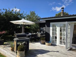 Holiday Home Yvette - 350m from the sea by Interhome في Hejlsminde: فناء مع مظلة وطاولة مع شواية +27 صورة