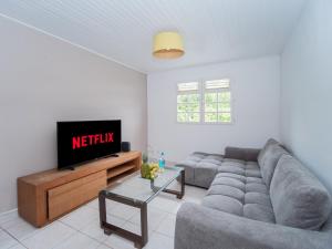 a living room with a couch and a tv at Villa Zenitude Caraïbes in Les Trois-Îlets