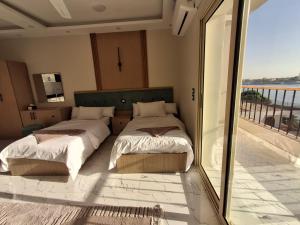 two beds in a room with a balcony at ElMena House Luxor in Luxor