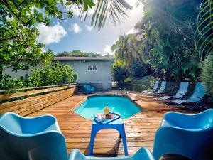 a swimming pool with chairs and a table in a backyard at Villa Zenitude Caraïbes in Les Trois-Îlets