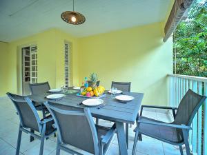 a blue table with chairs and a bowl of fruit on it at Villa Zenitude Caraïbes in Les Trois-Îlets