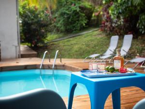 a blue table with a bottle of whiskey next to a pool at Villa Zenitude Caraïbes in Les Trois-Îlets