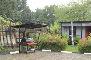 a grill in a garden next to a house at NL Josephine's Apartment in Kampala
