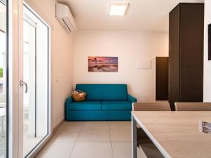 een blauwe bank in een woonkamer met een raam bij Apartment Iris Suite-3 by Interhome in Bibione