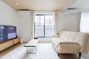 a living room with a white couch and a tv at AMBLE Asakusa in Tokyo