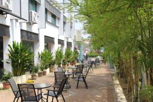 a row of tables and chairs on a sidewalk with plants at M Design Hotel @ Seri Kembangan in Seri Kembangan