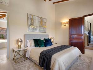 een slaapkamer met een groot bed met groene kussens bij Villa Cala Figuera in Santanyi