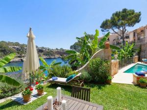 een achtertuin met een parasol en een zwembad bij Villa Cala Figuera in Santanyi