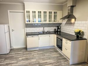 a kitchen with white cabinets and black counter tops at Apartment Samlen Vasselgård by Interhome in Herand +28 photos