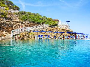 a beach with blue umbrellas and people in the water at Apartment Villa Le Palme by Interhome in Rio Marina