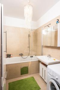 ein Badezimmer mit einer Badewanne, einem Waschbecken und einer Waschmaschine in der Unterkunft Sky View Apartment Vienna in Wien