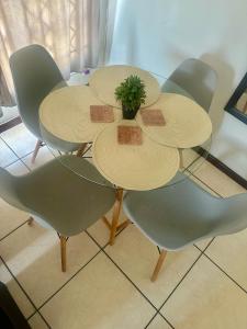 un tavolo con quattro sedie e una pianta sopra di Feel At Home Cosy Apartment a Gaborone Altre 9 foto