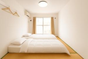 deux lits dans une chambre blanche avec une fenêtre dans l'établissement Sakura Hotel Nippori, à Tokyo