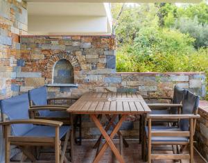 a wooden table and chairs in front of a stone wall at Villa Nefeli Skiathos in Skiathos Town