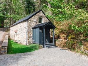 Un pequeño edificio de piedra con techo negro. en Holiday Home Wayside Bothy by Interhome, en Drumnadrochit