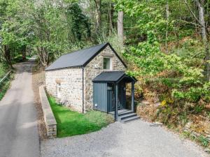 Un pequeño edificio con techo negro en una calle. en Holiday Home Wayside Bothy by Interhome, en Drumnadrochit