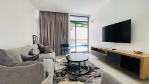 a living room with a couch and a flat screen tv at AGASARO LUXURY Apartment in Kigali