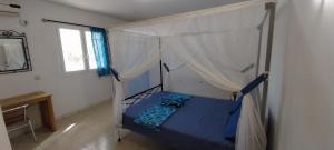 Le Ganalé في Warang: غرفة نوم مع سرير مع مظلة ومكتب